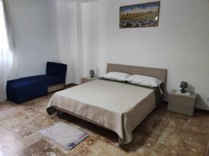 een slaapkamer met een bed en een blauwe stoel bij Appartamento Cuore Salento in Carmiano