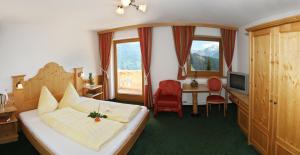 a hotel room with a bed and a desk and a television at Alpenkönig in Zell am Ziller