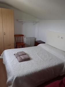 a bedroom with a large white bed and a chair at Apartamentos Santillán in San Vicente de la Barquera