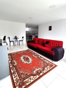 a living room with a red couch and a red rug at Hermoso apartamento en Popayán in Popayan