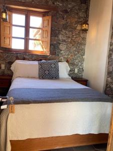 ein Schlafzimmer mit einem großen Bett und einer Steinmauer in der Unterkunft Hotel Amor y Paz in Real de Catorce