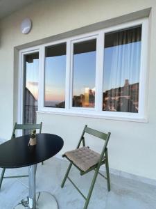 einen Tisch und Stühle in einem Zimmer mit Fenster in der Unterkunft Pisha Panoramic Rooms in Kruja