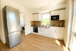 cocina con armarios blancos y nevera de acero inoxidable en 110 Lux Furnished flat, en Beaufort