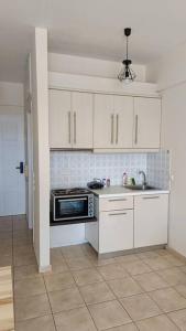 eine Küche mit weißen Schränken, einer Spüle und einer Mikrowelle in der Unterkunft Cozy Nights in Messini