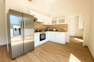cocina con armarios blancos y nevera de acero inoxidable en 320 Lux Furnished flat, en Beaufort