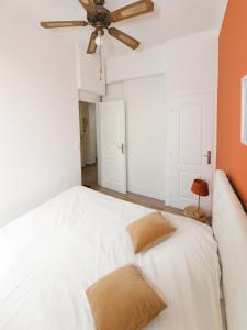 a bedroom with a white bed with a ceiling fan at Luciana Cannes avec parking - proximité centre croisette -gare -plage in Cannes