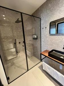 a glass shower in a bathroom with a sink at צימר אירוס ירוחם in Yeroẖam