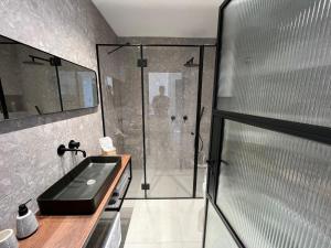 a bathroom with a glass shower and a sink at צימר אירוס ירוחם in Yeroẖam