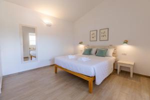 um quarto branco com uma cama e um espelho em B&B Natura em San Teodoro