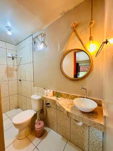 a bathroom with a toilet and a sink and a mirror at Pousada Recanto das Orquídeas in Barreirinhas