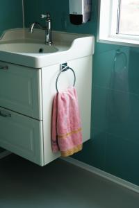 W łazience znajduje się umywalka i różowy ręcznik. w obiekcie Vík Hostel w mieście Vík