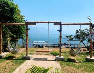 a swing park with the ocean in the background at Hotel Porto Bello in San Pedro La Laguna