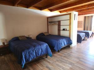 a bedroom with three beds in a room with wooden ceilings at Hostal Belen in San Pedro de Atacama