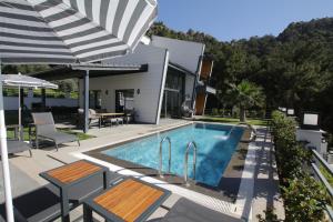 a swimming pool with two benches and an umbrella at Marin Villaları Villa-2 in Marmaris
