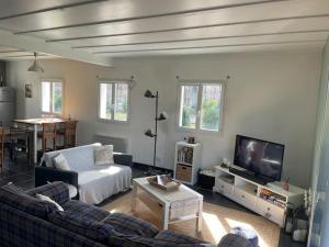 a living room with a couch and a tv at Maison proche du lac ! in Hourtin