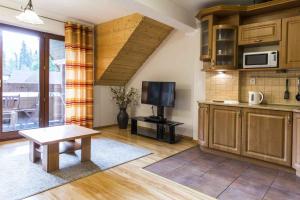 a kitchen with wooden cabinets and a table and a tv at Apartament Giewont in Kościelisko