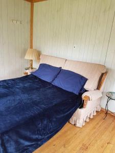 Un dormitorio con una gran cama azul y una mesa en Get away from it all Rock Elm, en Marion Bridge