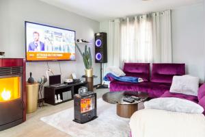a living room with purple furniture and a flat screen tv at Maison romantique entre deux fleuves chez l'habitant in Montereau-Fault-Yonne