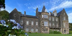 a large stone building with a blue sky in the background at Torloisk House in Kilninian