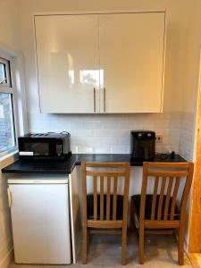 a kitchen with a counter with two chairs and a microwave at Mount nod rooms in London