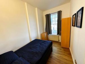 a bedroom with a blue bed and a window at Mount nod rooms in London