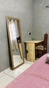 um espelho sentado ao lado de uma mesa e uma cama em Linda Kit Net Mobiliada Individual em Dourados