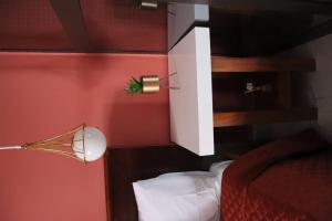 a bedroom with a red wall with a bed and a lamp at Casa 2 in Namibe