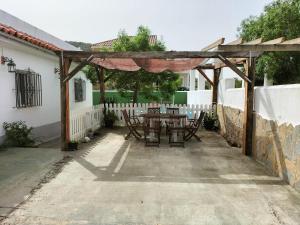 een houten pergola met een tafel en stoelen op een patio bij El Capricho in Benalup Casas Viejas