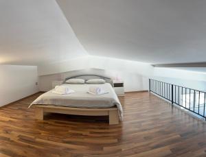 a white bedroom with a bed and a wooden floor at Apartment Štucin in Vipava