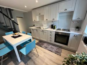 a kitchen with white cabinets and a table and chairs at Limes Cottage in Cowbridge