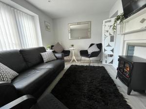 a living room with a black couch and a fireplace at Limes Cottage in Cowbridge