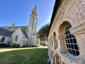 um antigo edifício de pedra com uma torre e uma igreja em La Pommedepin Ravissante maisonnette avec jardin em Plouescat