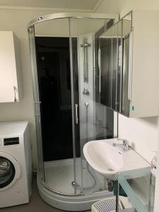 a bathroom with a shower and a sink and a washing machine at Velkommen til en koselig leilighet på Sørlandet! in Kristiansand