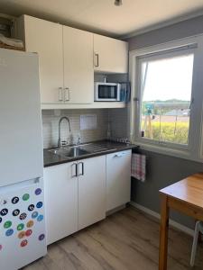 a kitchen with white cabinets and a sink and a window at Velkommen til en koselig leilighet på Sørlandet! in Kristiansand