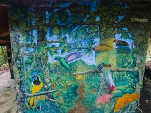 a painting of two birds on a tree at Bosque de Oro in Apía