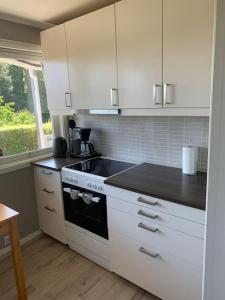 a kitchen with white cabinets and a black counter top at Velkommen til en koselig leilighet på Sørlandet! in Kristiansand