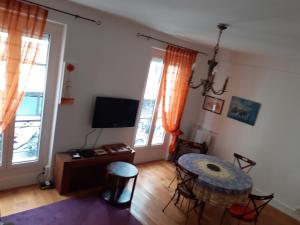 a living room with a table and a television at Appartement Petroff in Paris