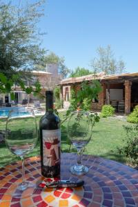 a bottle of wine sitting on a table with two glasses at Posada Boutique El Encuentro Chacras de Coria in Chacras de Coria