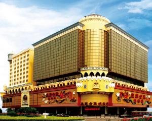 un grand bâtiment jaune avec une horloge. dans l'établissement Casa Real Hotel, à Macao