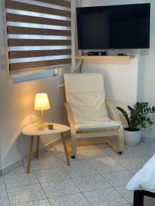 krzesło i stół z lampką i telewizorem w obiekcie Little apartment w mieście Patras