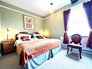 a bedroom with a bed and a chair and a window at Colthrop Manor B&B in Thatcham