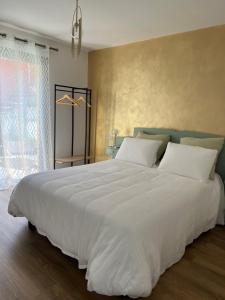 ein großes weißes Bett in einem Schlafzimmer mit Fenster in der Unterkunft Mon Rêve in Breil-sur-Roya