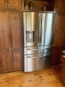 un frigorifero in acciaio inossidabile in una cucina con mobili in legno di Dancing Barefoot Farms a Pawlet
