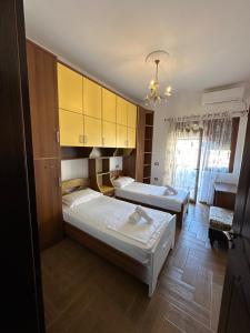 two beds in a room with yellow cabinets at Rus Apartment in Berat