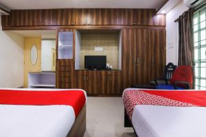 Cette chambre comprend deux lits et une télévision. dans l'établissement OYO Flagship Maheshwari Villas, à Chennai