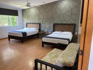 ein Schlafzimmer mit zwei Betten und einem Sofa darin in der Unterkunft Tonantzincalli SPA Prehispanico in Chiconcuac