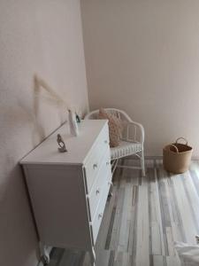 biała komoda w pokoju z krzesłem w obiekcie La villa des jonquilles spa détente w mieście Saint-Victor