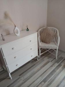 una cómoda blanca y una silla en una habitación en La villa des jonquilles spa détente en Saint-Victor