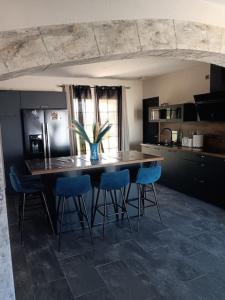 a kitchen with a table with blue chairs and a refrigerator at La villa des jonquilles in Saint-Victor