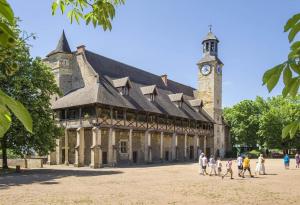 a large building with a clock tower with people walking in front at La villa des jonquilles in Saint-Victor